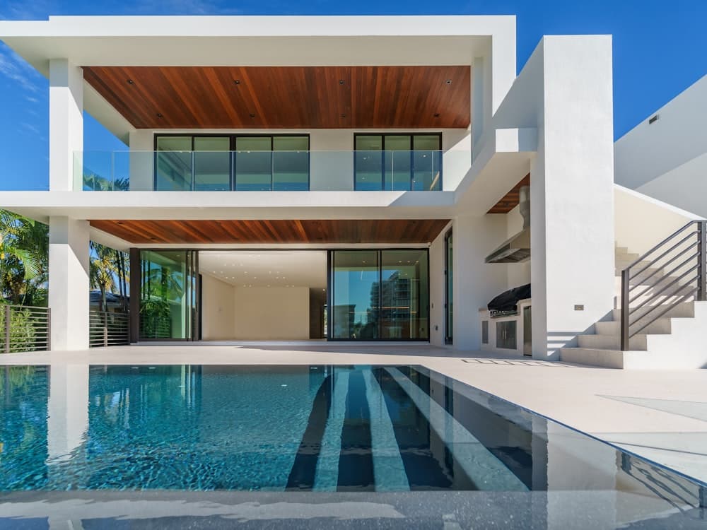 Modern two-story home addition in white render and warm timber with a pool
